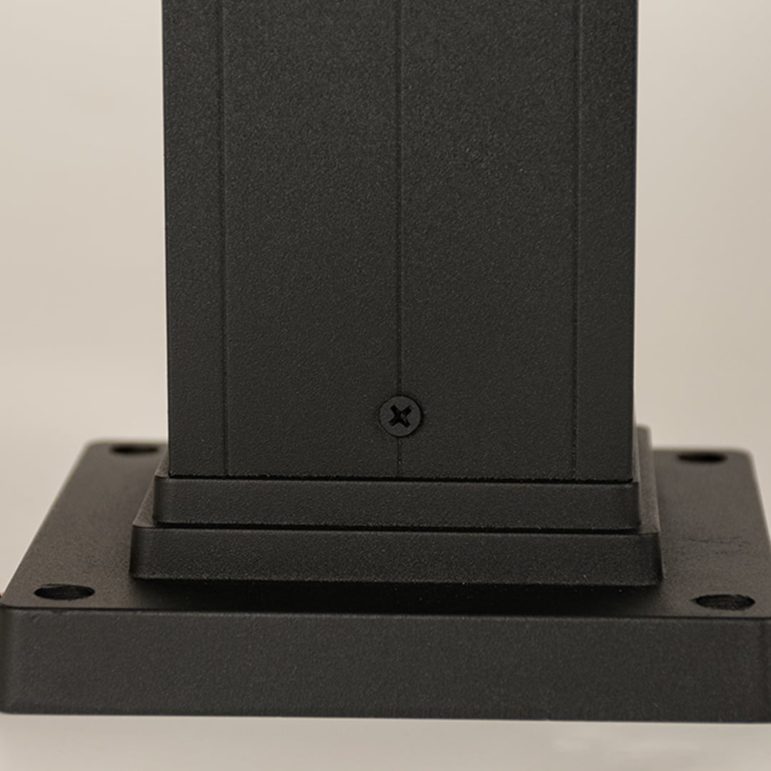 A detailed closeup focusing on the glowing bulb inside the ribbed glass panel of the outdoor bollard light showing warm illumination and refined craftsmanship.