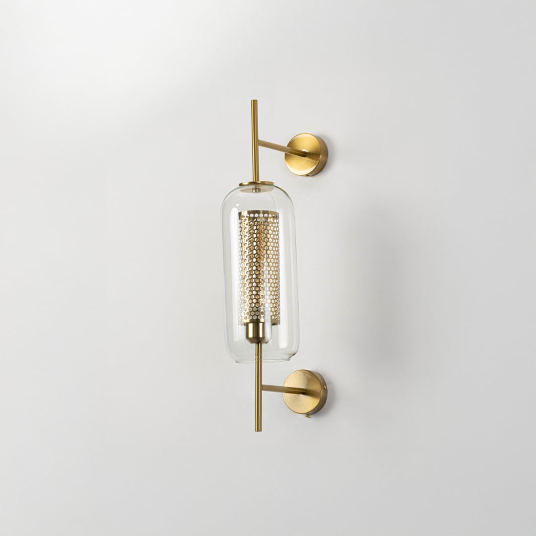 Contemporary wall lamp with gold finish and clear glass shade ideal for bedroom or living room wall decoration.