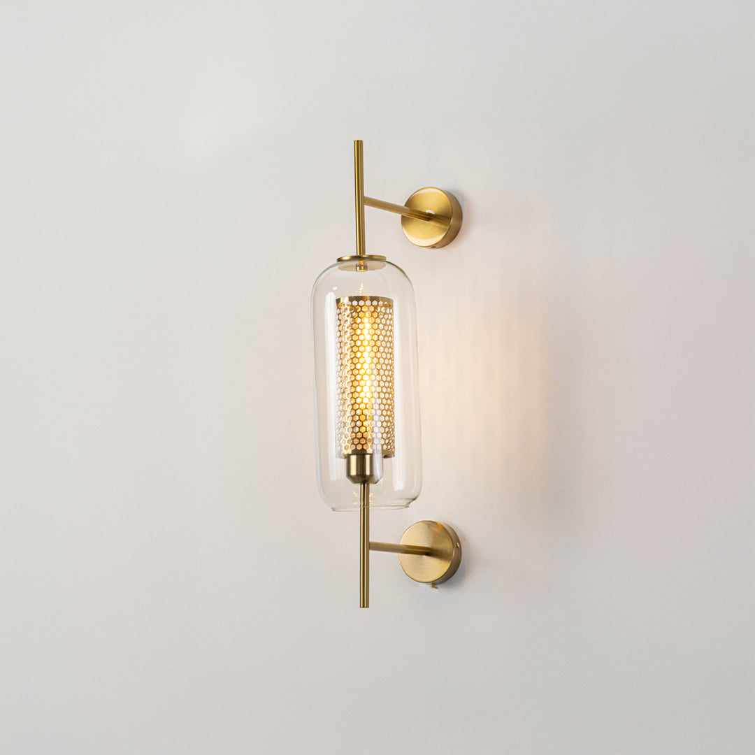 Minimal cylindrical glass wall light with gold metal mount fixed on clean white wall background perfect for elegant modern interior lighting.

