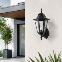 Traditional black metal outdoor wall lantern with ornate design for porch entrance garden and exterior walls with warm lighting.