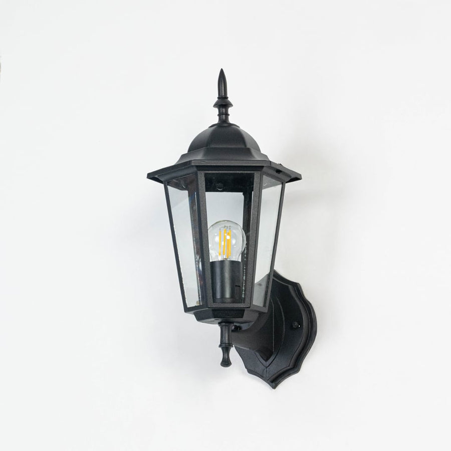 Outdoor wall lantern in matte black finish shown off on white background with clear glass panes and clean detailing.