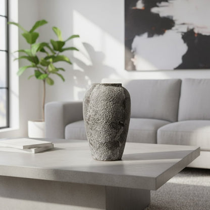 Textured ceramic decor vase styled on a modern coffee table in a bright living room with sofa artwork and indoor plant creating a calm minimal interior scene.
