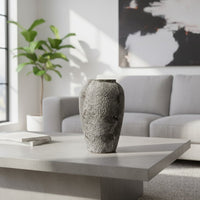 Textured ceramic decor vase styled on a modern coffee table in a bright living room with sofa artwork and indoor plant creating a calm minimal interior scene.