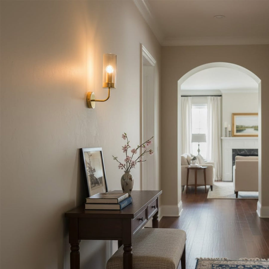 Contemporary brass wall light creating warm ambient lighting in luxury hallway and living room interiors.