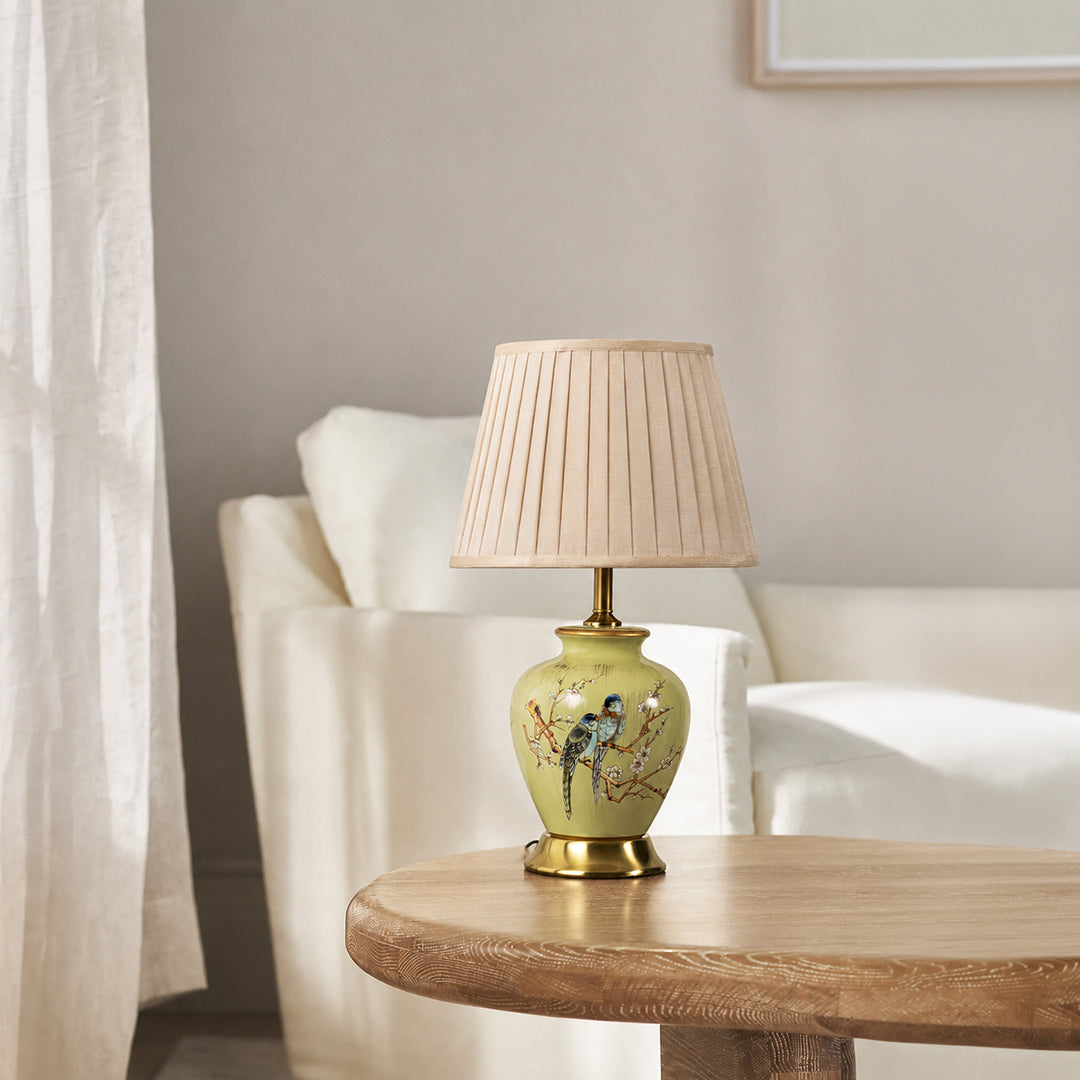 Floral ceramic table lamp with pleated fabric shade and gold accents styled for elegant bedroom and living room decor.