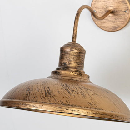 Closeup of vintage gold wall light showing curved arm dome shade textured finish and rustic exterior lighting craftsmanship.