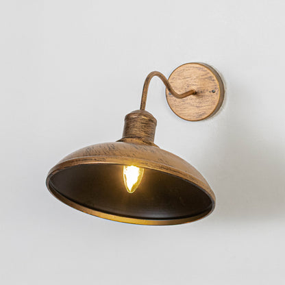 Vintage bronze metal wall light on white background with dome shade for rustic industrial decor.
