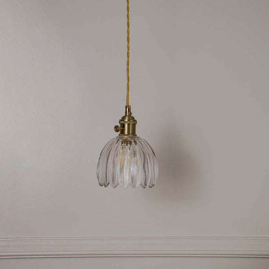 Clear ribbed glass pendant light with antique brass fittings crafted for elegant contemporary interiors.
