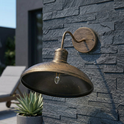 Vintage brass outdoor wall light mounted on modern stone wall, industrial style exterior sconce with warm bulb, patio garden setting