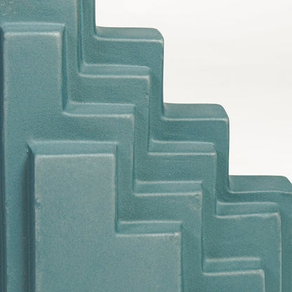 Detailed closeup of teal ceramic stepped decorative sculpture showcasing layered geometric edges and matte surface.