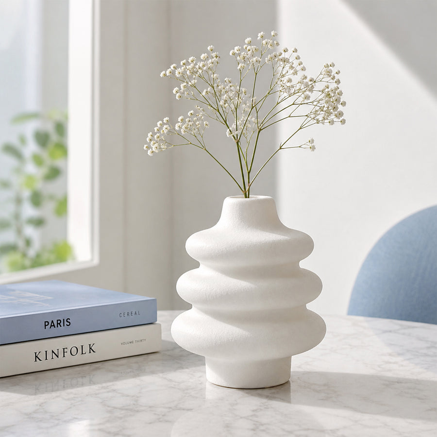 White textured ceramic flower vase with dried blooms placed on marble table for modern decor styling.
