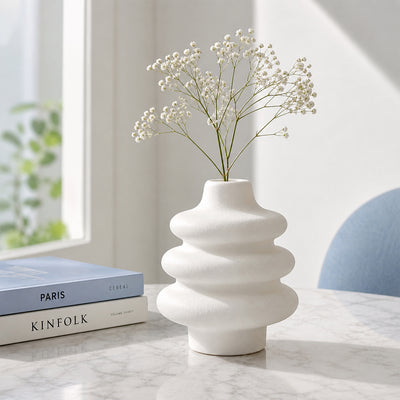 White textured ceramic flower vase with dried blooms placed on marble table for modern decor styling.