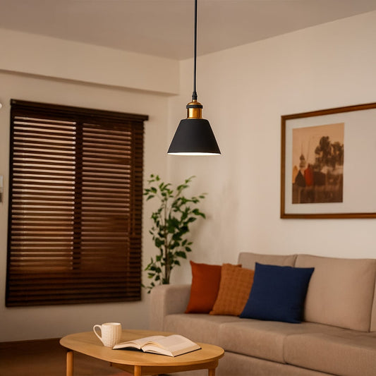 Black cone pendant light glowing warmly above a wooden coffee table in a cozy modern living room with a beige sofa and colorful cushions.