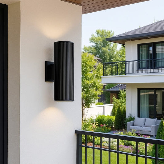 Tall black cylindrical wall light illuminating a modern entryway with elegant glow and contemporary architectural appeal.