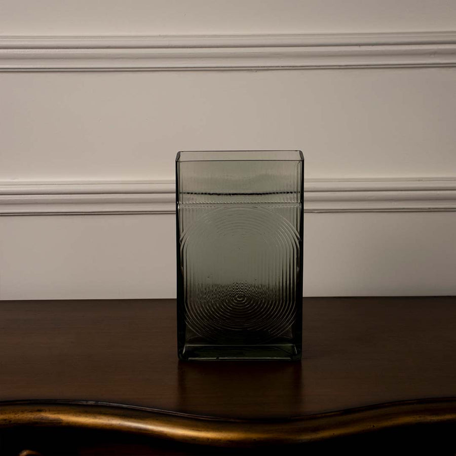 Sleek smoke grey glass vase on dark wooden table for minimalist home decor and refined office desk styling needs.