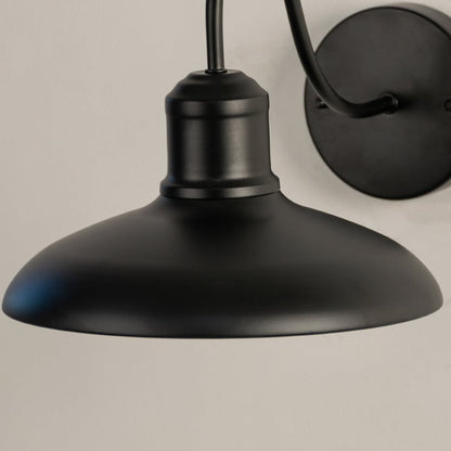 Closeup of matte black outdoor wall light highlighting its wide metal shade and clean industrial detailing.