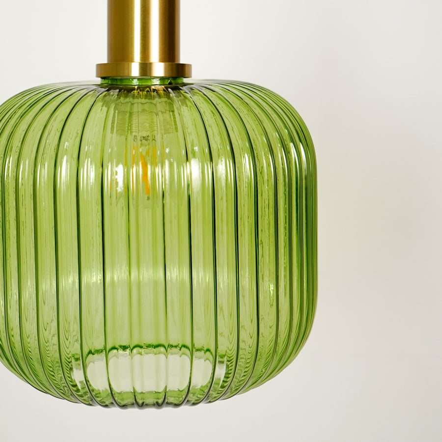 Closeup of green ribbed glass pendant light with brass canopy highlighting premium craftsmanship and texture.