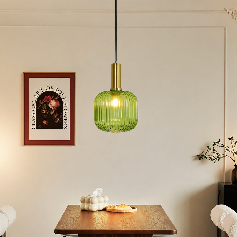 Green glass pendant light with brass fixture suspended above dining area creating cozy modern ambiance.