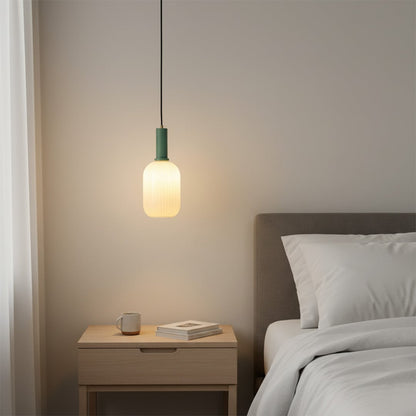 White ribbed glass pendant light with brass accents beside bed creating warm modern bedroom lighting ambiance.