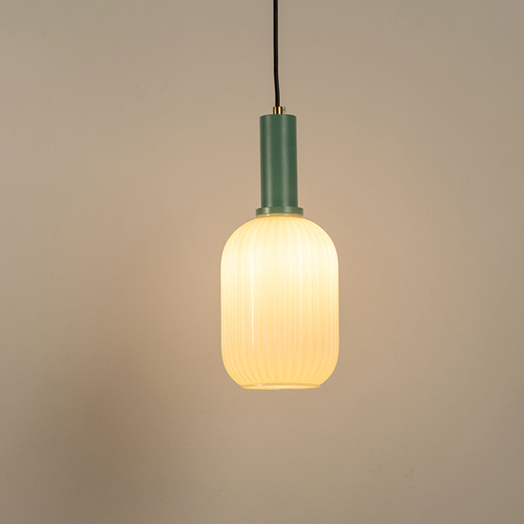 Frosted glass pendant light with green holder and soft warm glow on neutral background minimal lighting ideal for bedroom and dining decor.