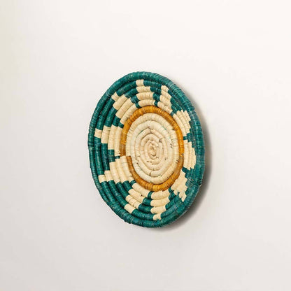 Side view of handcrafted teal seagrass wall basket with woven sunrise pattern for artisan boho home décor.
