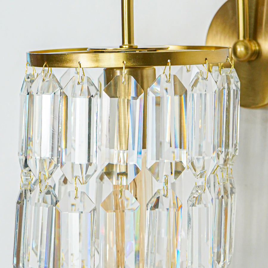 Close view of gold wall light with premium crystal prisms reflecting warm light creating luxurious ambiance in modern home interior.