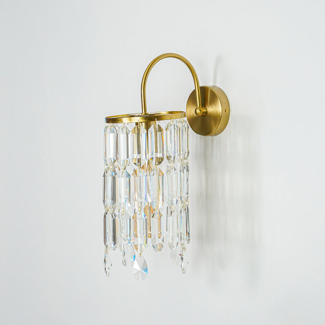 Elegant gold wall mounted light with clear crystal strands hanging in minimal interior setting ideal for hallway or bedroom decorative lighting.