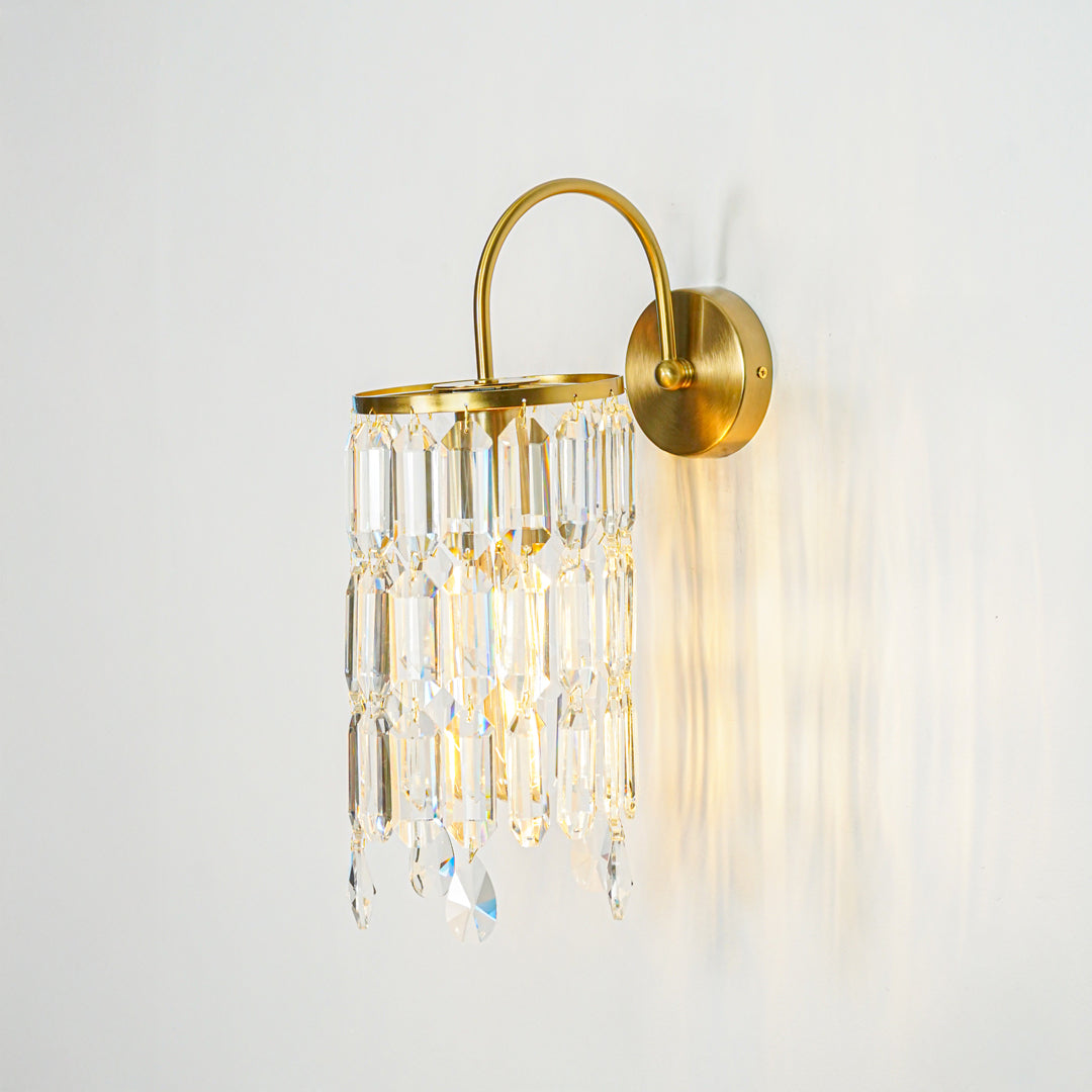 Modern gold metal wall sconce with cascading crystal glass drops on beige wall background perfect for luxury interior accent lighting setup.