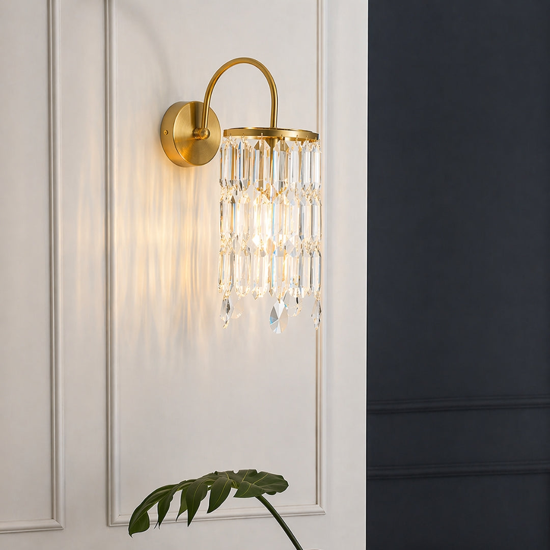 Gold wall light with crystal hanging prisms mounted on soft neutral wall background ideal for elegant living room or bedroom decor lighting.