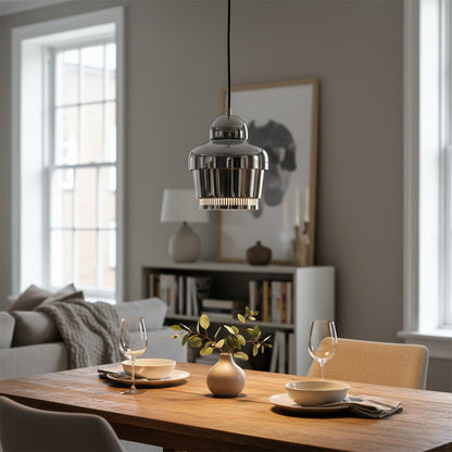 Glass pendant light with metallic finish hanging above wooden dining table adding soft ambient glow to modern dining space.