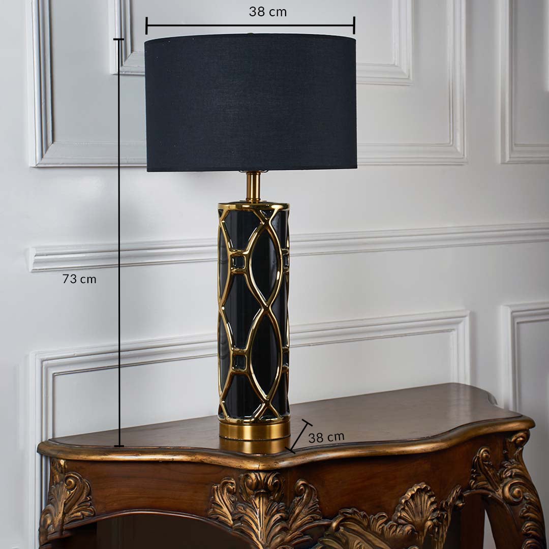 Black shade gold patterned table lamp with size 73cm height and 50cm width on carved console table with light off for bold luxury décor.