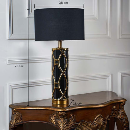 Black shade gold patterned table lamp with size 73cm height and 50cm width on carved console table with light off for bold luxury décor.