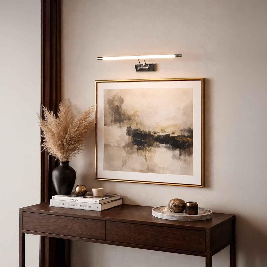 Gold metal picture light illuminating framed artwork above console table creating elegant gallery inspired interior decor.