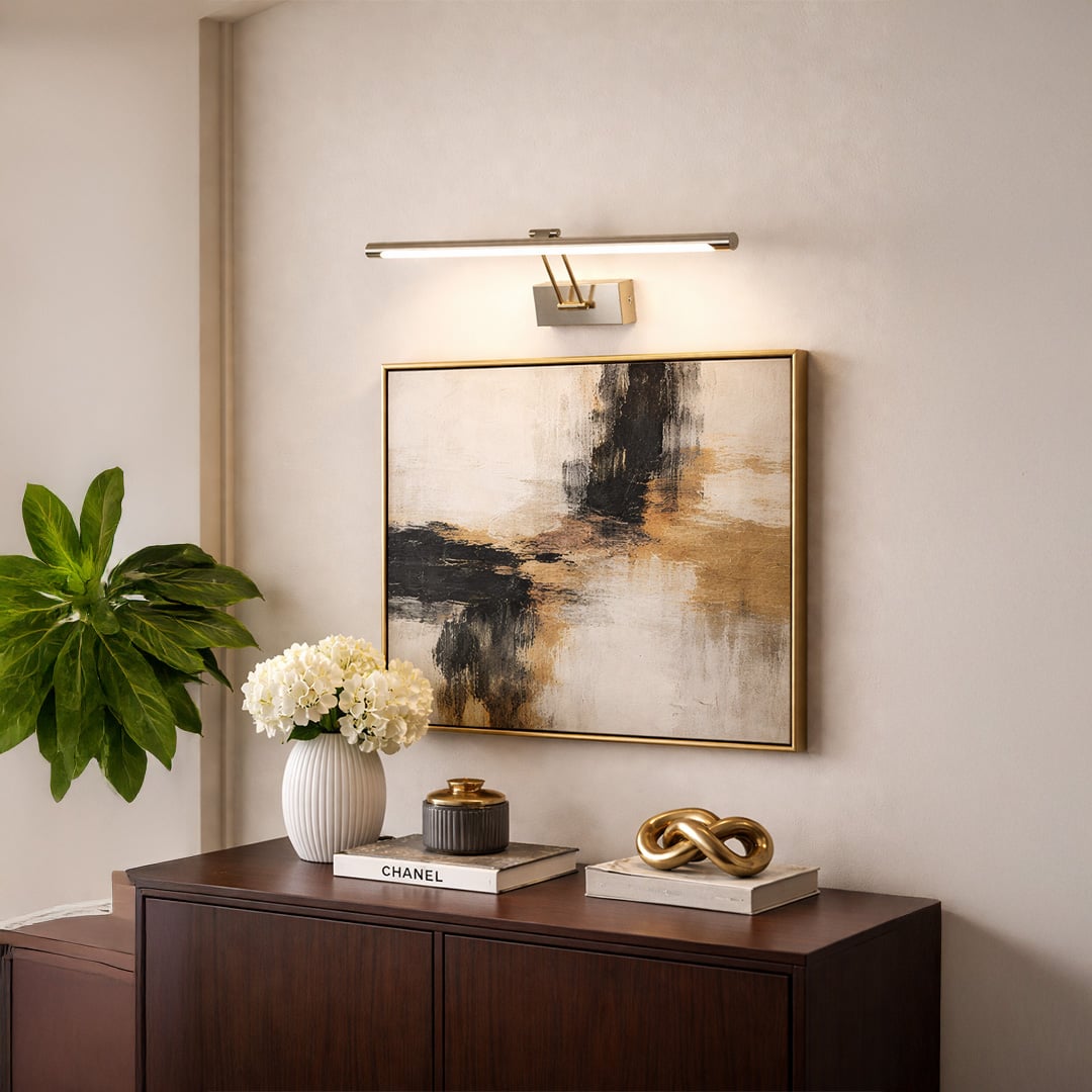 Gold metal picture light enhancing abstract wall art with warm illumination above console table in modern interiors.