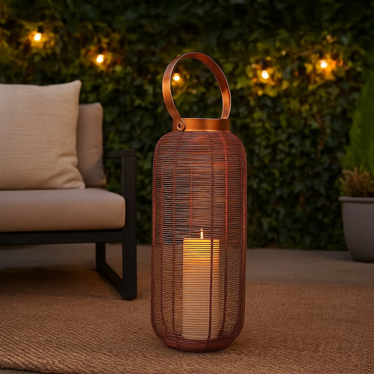 Elegant copper wire lantern with illuminated LED candle creating a warm glow on an outdoor patio rug next to a modern sofa for evening ambiance.