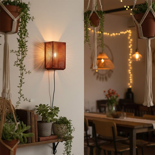 Boho style rectangular red woven wall sconce casting a warm glow next to indoor plants and a wooden dining room table setting.