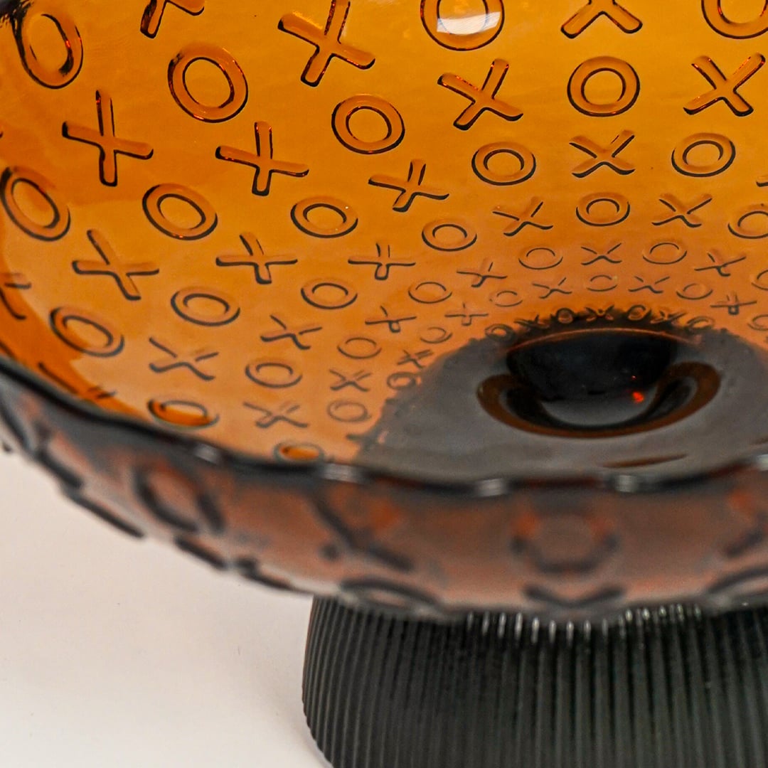 Closeup of amber glass decorative bowl with intricate patterned texture highlighting premium craftsmanship and styling.