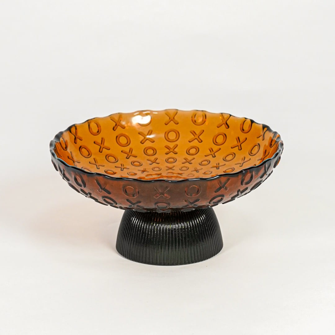 Amber glass decorative bowl with black pedestal base for elegant tabletop styling and contemporary home decor.