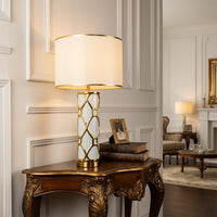 White shade gold frame table lamp on crafted console table with light on for luxurious decorative home décor.
