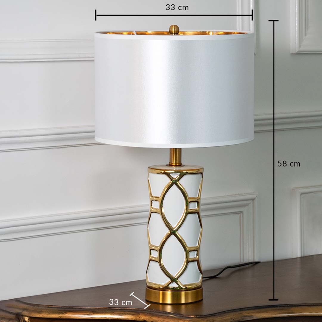 White and gold ceramic table lamp with fabric shade shown with 58 cm height and 33 cm width for decorative detailing.