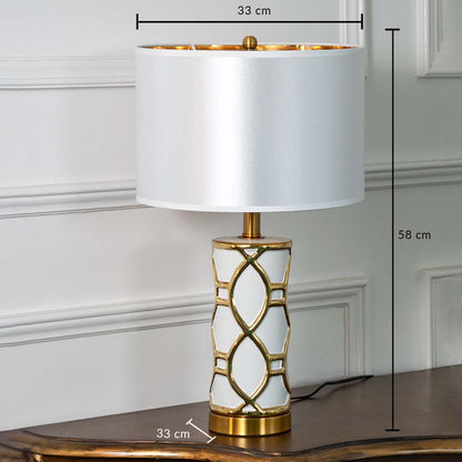 White and gold ceramic table lamp with fabric shade shown with 58 cm height and 33 cm width for decorative detailing.