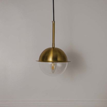 Brass metal pendant light with clear bulb and dome shade crafted for elegant modern interiors.