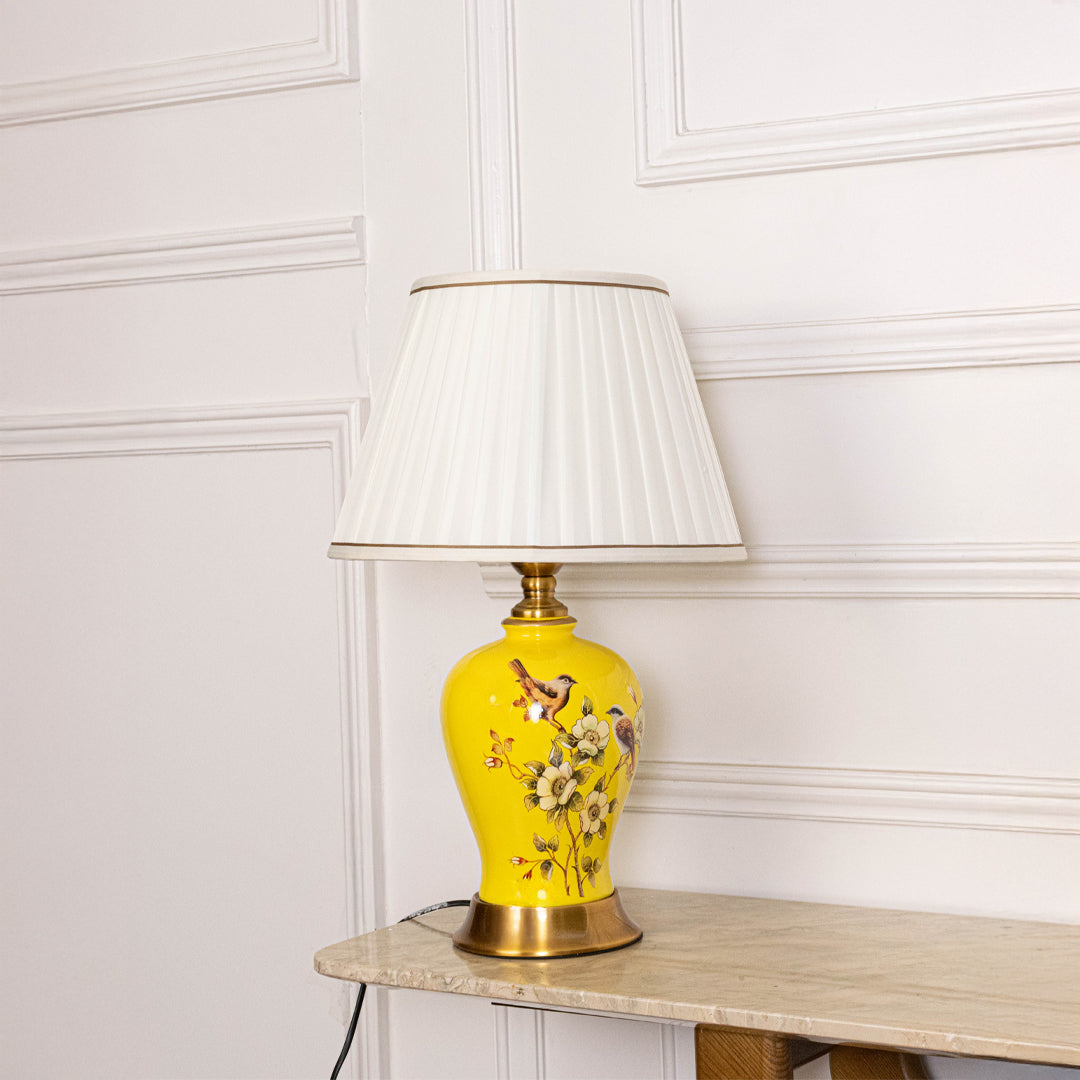 Yellow floral ceramic table lamp with fabric shade placed on a side table creating elegant traditional ambient lighting.