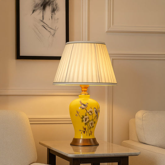 Table lamp with yellow ceramic base and white pleated shade styled on a marble table for bright elegant home decor.
