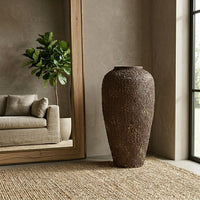 Brown textured floor vase placed beside sofa for elegant rustic modern living room decor styling.