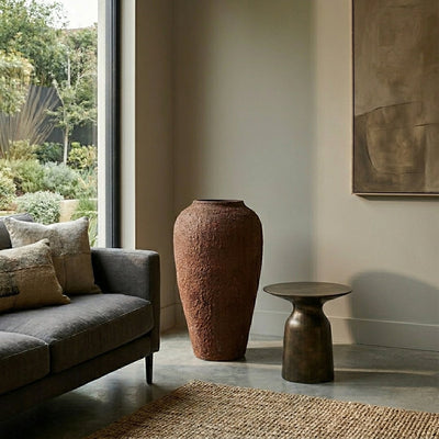 Brown textured floor vase placed beside sofa for elegant modern living room decor styling.