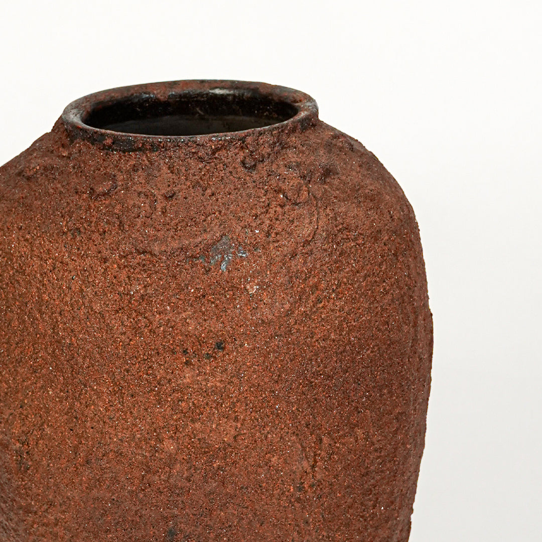 Closeup image of terracotta ceramic decorative vase for rustic tabletop decor styling with textured matte finish.