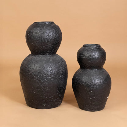 Black textured decorative vase displayed with other modern decor items creating a bold grouped arrangement for stylish home interiors.