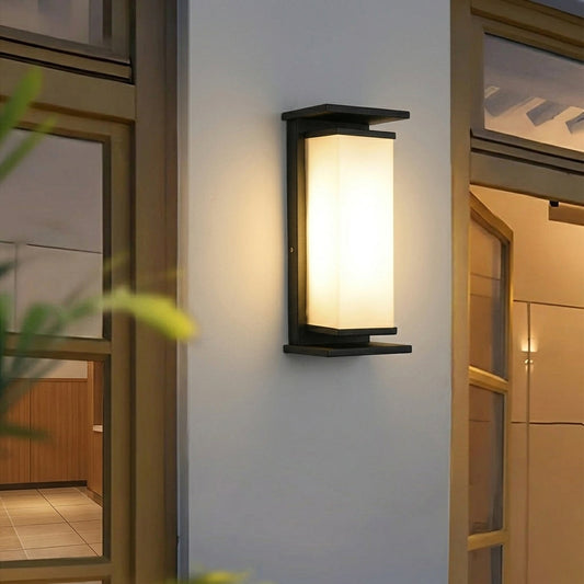 Modern outdoor wall light with frosted glass panel mounted beside door on exterior wall creating warm welcoming entrance lighting.
