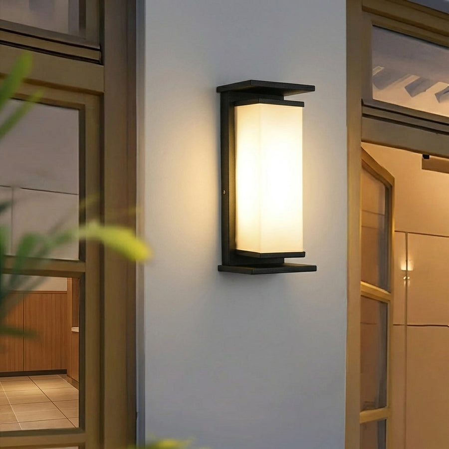 Modern outdoor wall light with frosted glass panel mounted beside door on exterior wall creating warm welcoming entrance lighting.